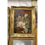 A still life of flowers in a vase on a ledge, oil on canvas, in a decorative gilt frame.