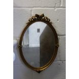 A gilt framed oval mirror.