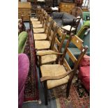 A set of eight modern oak ladder back dining chairs with rush seats, two with arms.