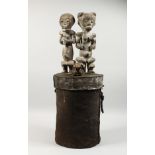 A LARGE EARLY NATIVE CIRCULAR BOX, the cover carved with two figures and a skull. 32ins high.