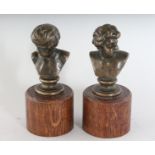 A SMALL PAIR OF GRAND TOUR BRONZE BUSTS on wooden bases. 3.5ins high.