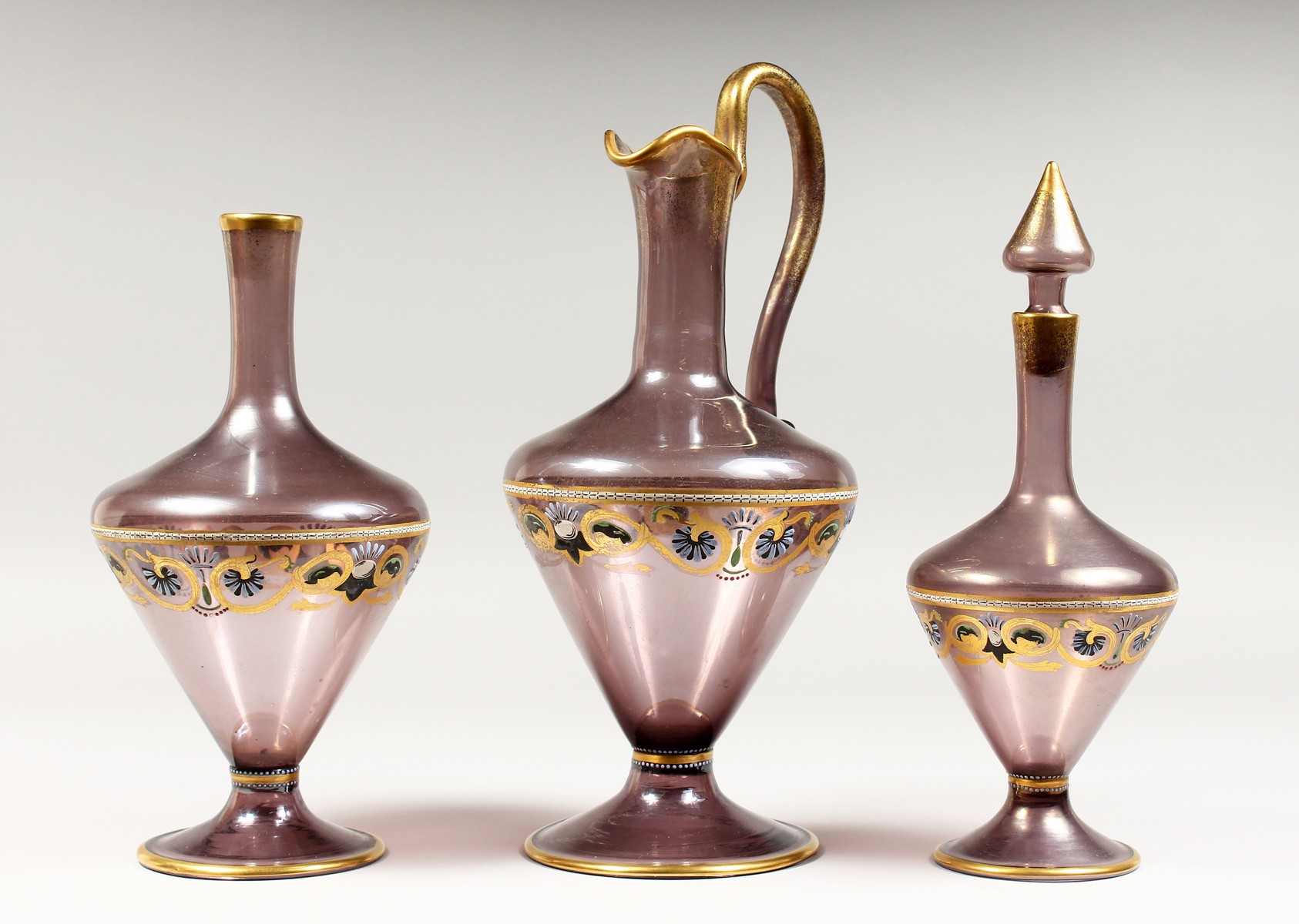 A VENETIAN AMETHYST TINTED GLASS EWER, with gilt and enamel decoration; together with the matching