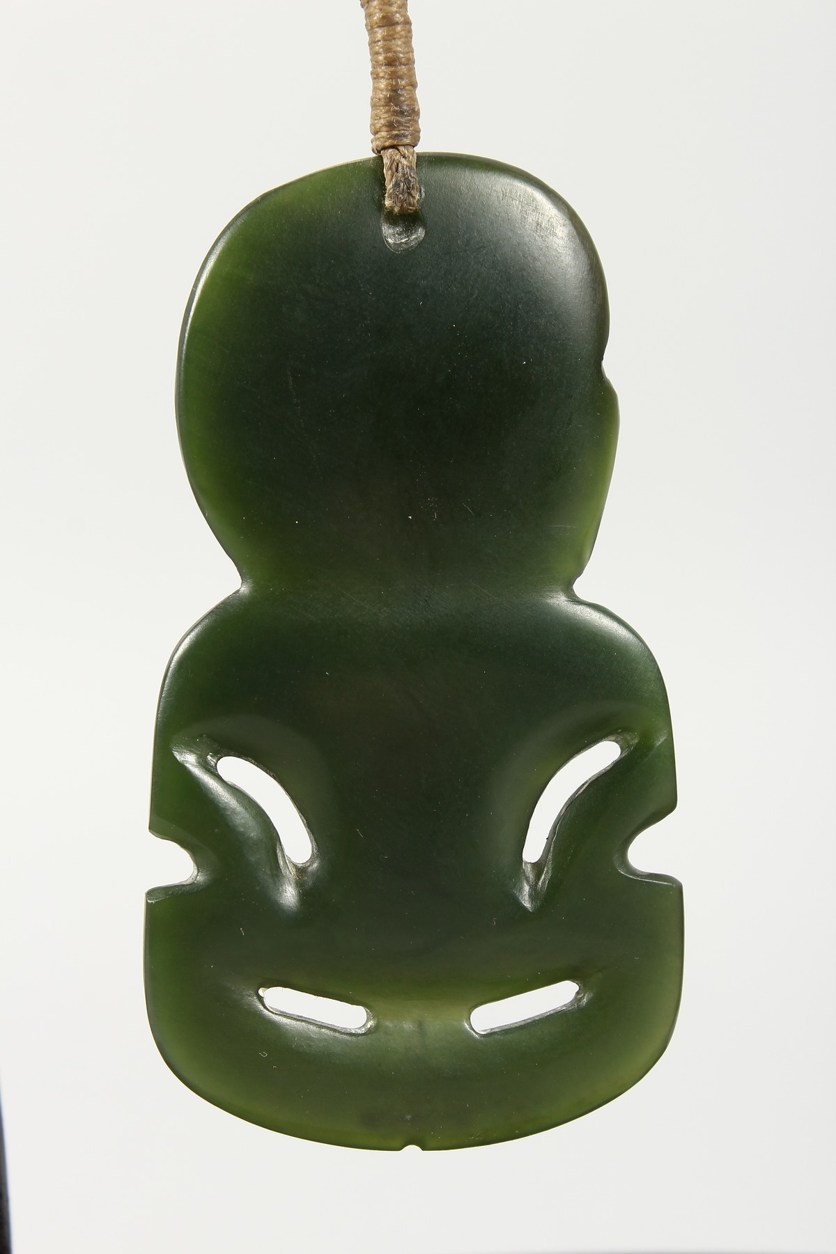 A NEW ZEALAND CARVED JADE TIKKI, suspended from a hardwood frame. Tikki: 2.75ins high. - Image 5 of 5