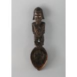 A CARVED WOOD TRIBAL SPOON. 9.5ins long.