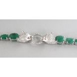 A CARTIER DESIGN SILVER, EMERALD SET AND PANTHER HEAD BRACELET.