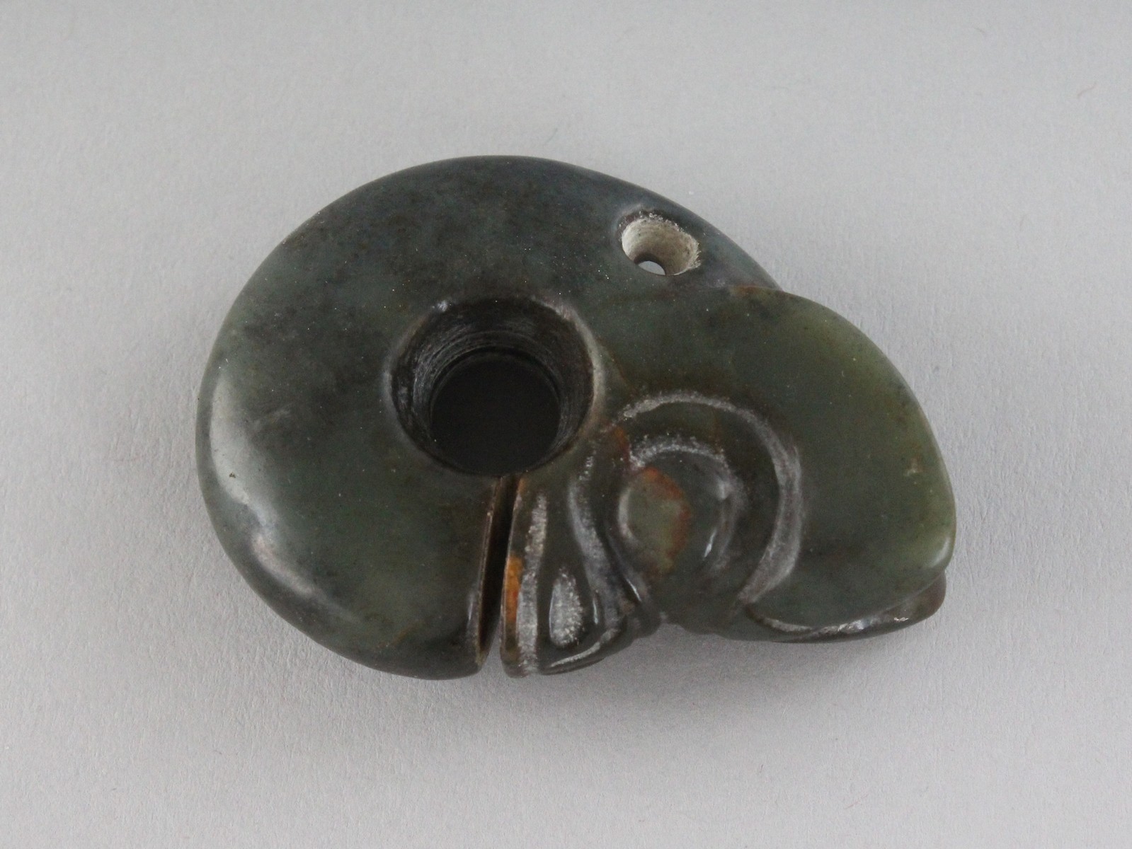 A CARVED JADE AMULET, a "head". 2.25ins.