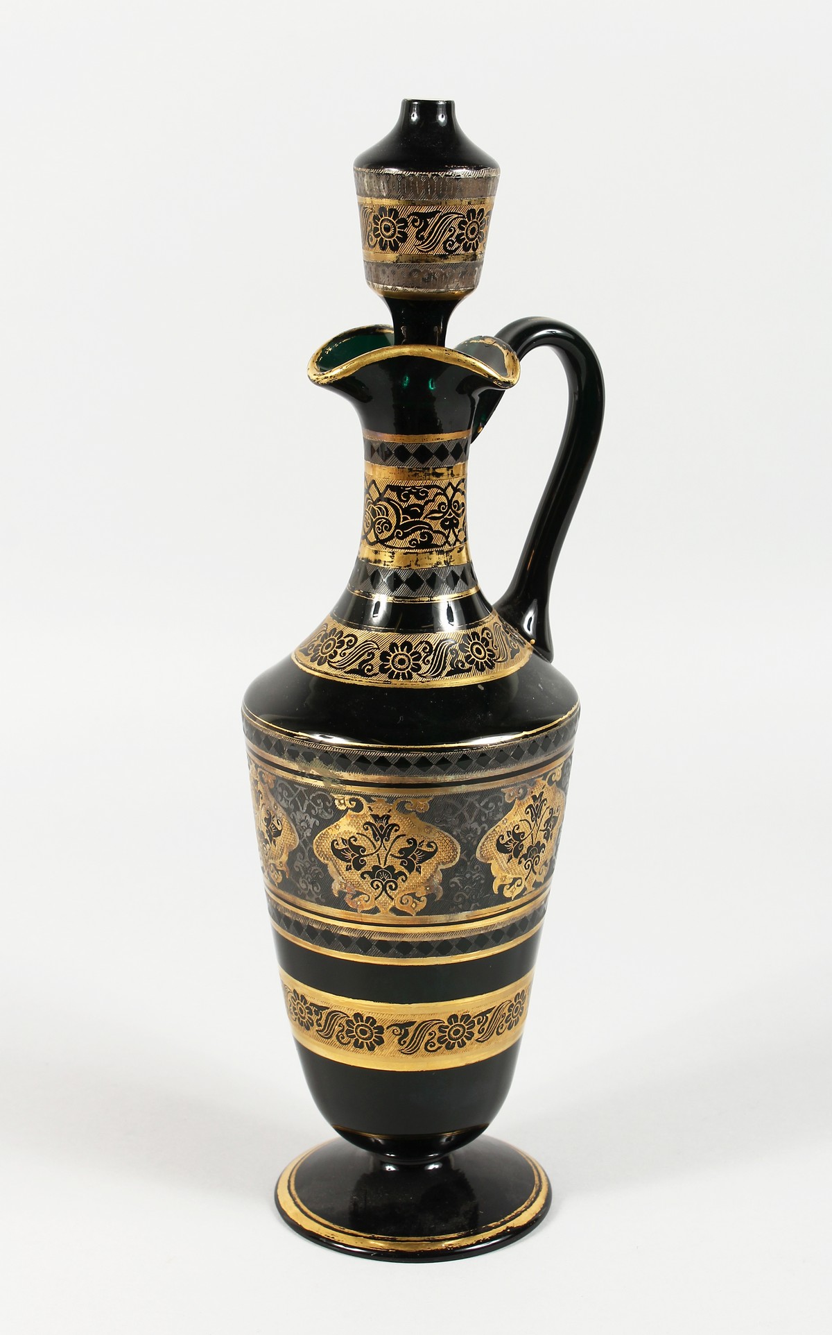 A CONTINENTAL DARK GREEN GLASS EWER AND STOPPER, with etched and gilded decoration. 14ins high.