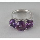 A SILVER THREE-STONE OVAL CUT AMETHYST RING.