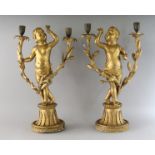A PAIR OF CARVED AND GILDED CHERUB CANDLESTICKS with two branches, on circular bases. 20ins high.