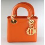 AN ORANGE LEATHER HANDBAG. 6.5ins wide.