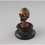 A SMALL CARVED BONE SKULL in a circular wooden box. 1.25ins.