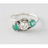 AN 18CT GOLD THREE-STONE DIAMOND AND EMERALD RING.