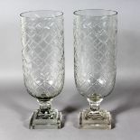 A PAIR OF SLICE CUT CIRCULAR GLASS STORM LAMPS on square stepped bases. 16ins high.
