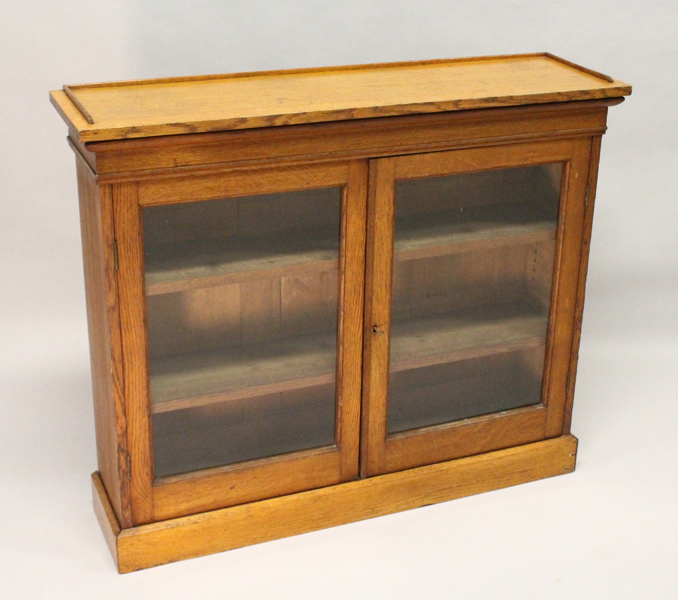 A VICTORIAN LIGHT OAK TWO-DOOR BOOKCASE, with a pair of glazed doors enclosing adjustable shelves,