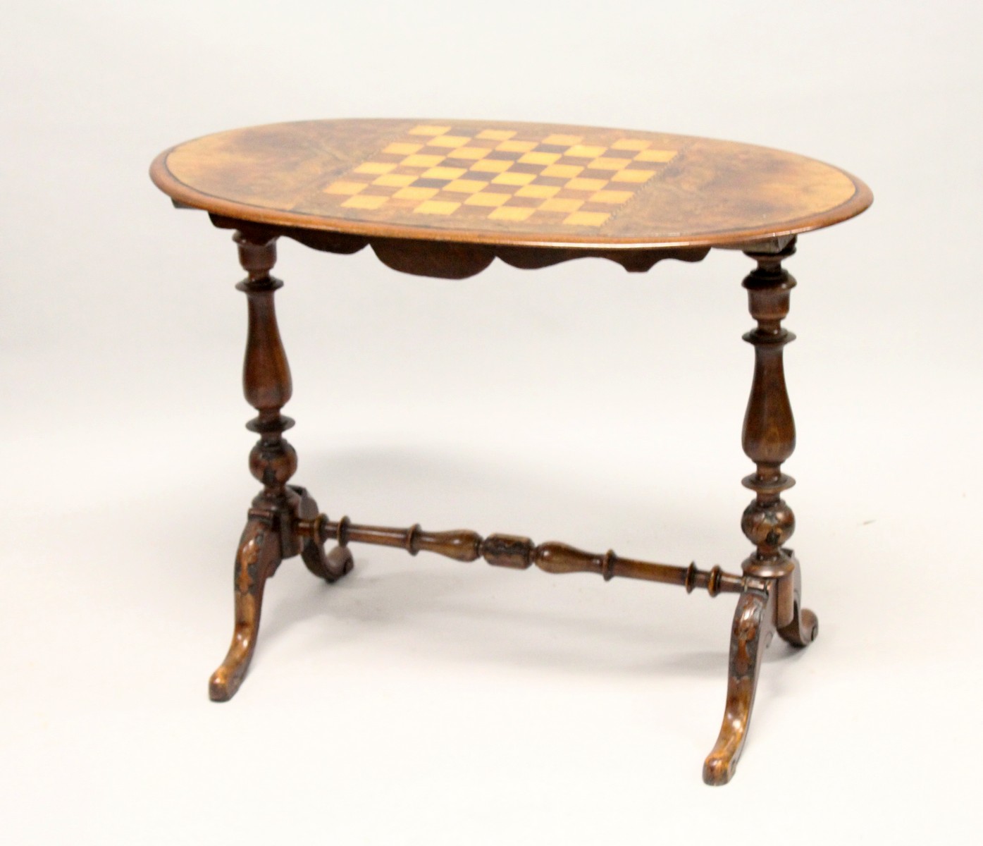 A VICTORIAN BURR WALNUT OVAL STRETCHER TABLE, the top inlaid with a games board. 3ft 1.5ins long x