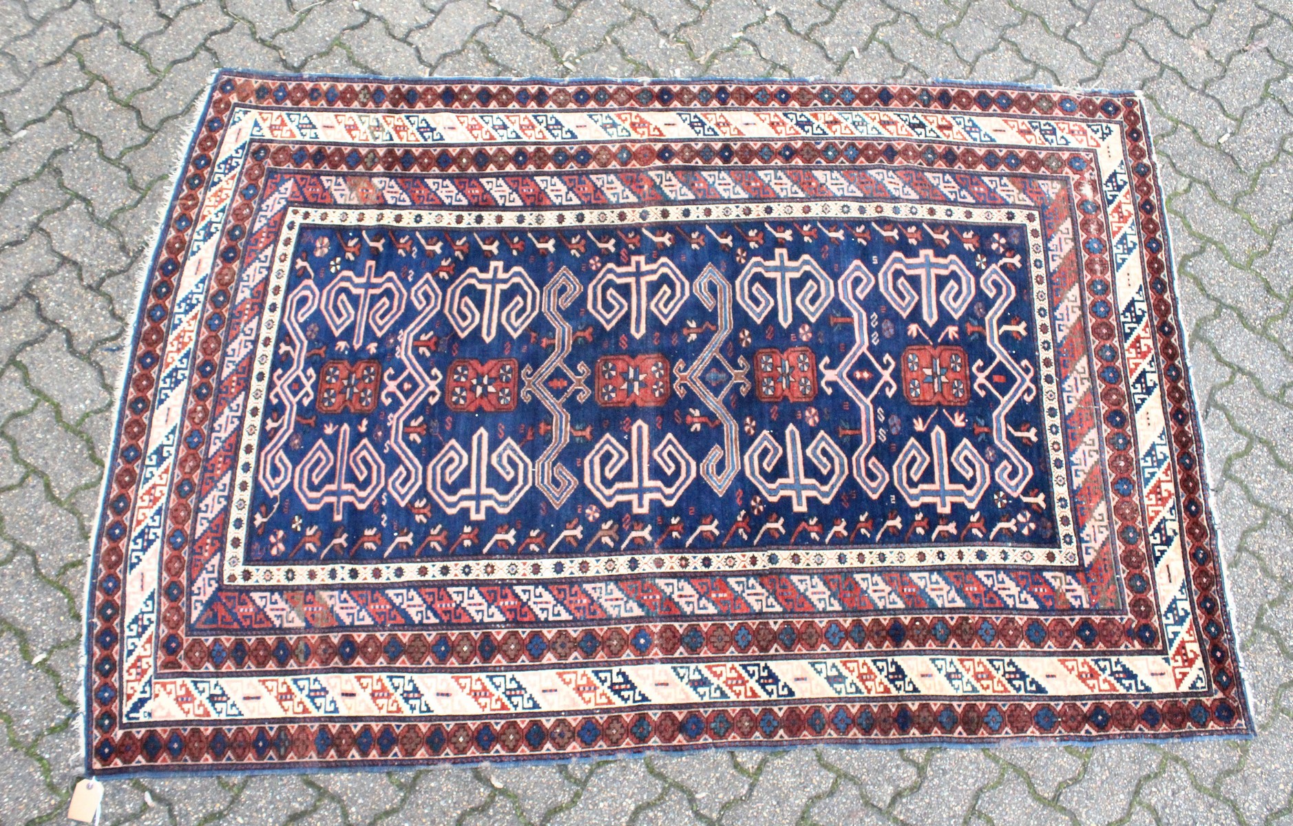 A CAUCASIAN RUG, mid 20th century, dark blue ground with stylised decoration within a five row