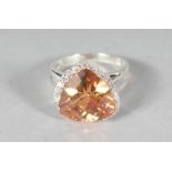 A SILVER ORANGE CZ HEART SHAPED RING.