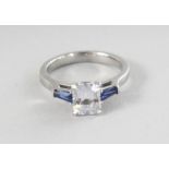 A PLATINUM OCTAGON WHITE SAPPHIRE RING, 1.65cts, and two blue sapphires, 0.32cts, on the shoulders.