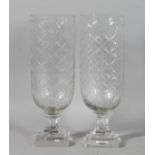A SMALL PAIR OF CUT GLASS STORM LAMPS on square bases. 13.5ins high.