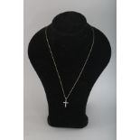 A 9CT GOLD DIAMOND SET CROSS on a chain.