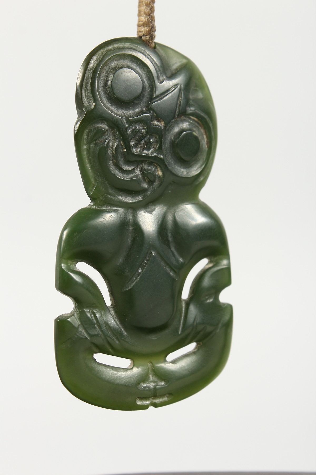 A NEW ZEALAND CARVED JADE TIKKI, suspended from a hardwood frame. Tikki: 2.75ins high. - Image 2 of 5