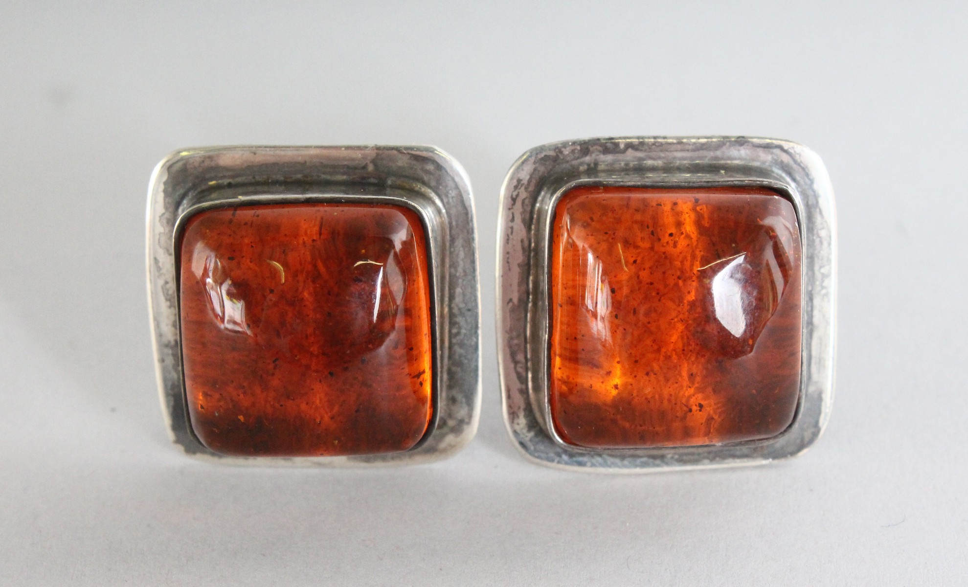 A LARGE PAIR OF SILVER AND AMBER EAR CLIPS.