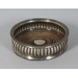 A GEORGE III SILVER WINE COASTER with turned wood base. 5.5ins diameter. London 1817.