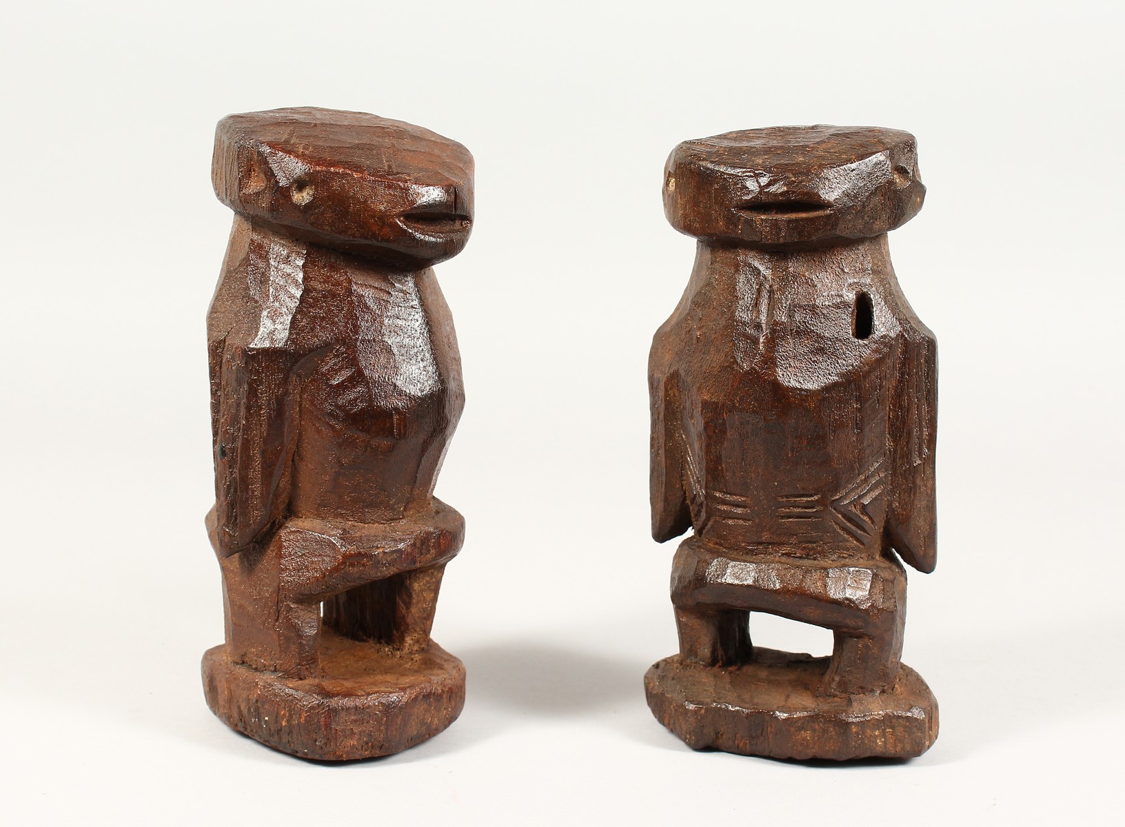 AN UNUSUAL PAIR OF TRIBAL CARVED WOOD STANDING FIGURES. 8ins high.