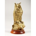 A CAT BRASS MODEL OF AN OWL ON A TREE STUMP, mounted on a circular wooden base. 12ins high.