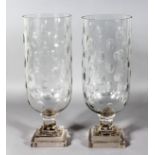 A PAIR OF OVAL CUT CIRCULAR GLASS STORM LAMPS on square stepped bases. 16ins high.
