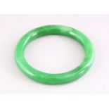 A CHINESE GREEN JADE BANGLE, 8.5cm diameter.