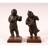 A PAIR OF SMALL CHINESE CAST BRONZE FIGURES OF YOUNG BOYS, holding items in their hand, showing