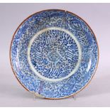 AN EARLY SAFAVID BLUE & WHITE PORCELAIN PLATE, decorated with scrolling floral design, (AF) 22cm.