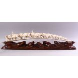 AN UNUSUAL EARLY 20TH CENTURY CARVED IVORY TUSK BRIDGE, on wooden stand, carved as a group of eleven
