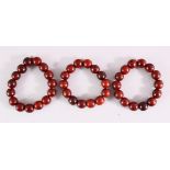 THREE RED SANDLEWOOD BEAD BRACELETS and various loose beads.