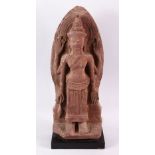 A 12TH CENTURY STYLE CAMBODIAN KHMER STYLE RED SANDSTONE CARVING OF A FOUR ARMED DEITY. 52cms high.