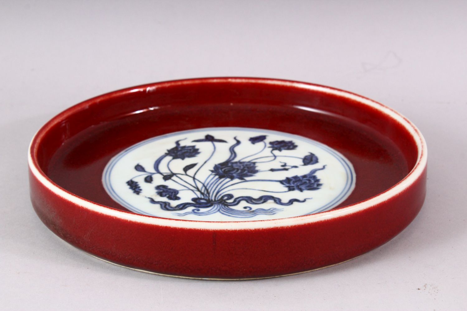 A MING STYLE COPPER RED CIRCULAR PORCELAIN DISH, the central blue and white panel painted with lotus - Image 3 of 5