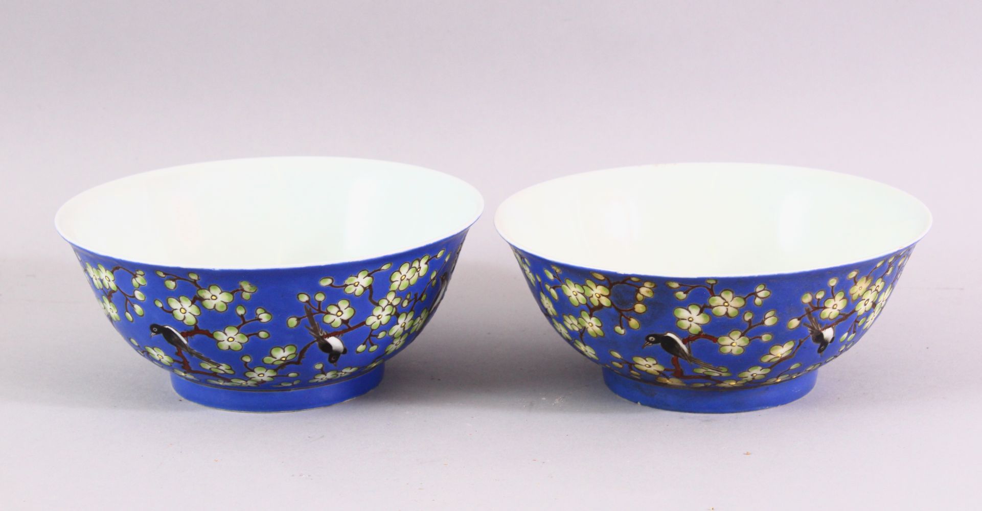 A PAIR OF CHINESE BLUE GROUND PORCELAIN BOWLS, each decorated with birds perched on blossoming