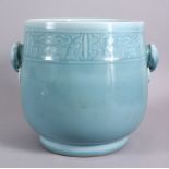 A CHINESE CELADON GROUND TWIN HANDLE PORCELAIN POT, with carved ruyi and chilong decoration, the