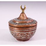 AN ISALMIC CIRCULAR COPPER AND SILVER INLAID BOX AND COVER, the cover with brass crescent shaped