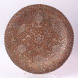 AN EARLY 20TH CENTURY ISLAMIC SILVER INLAID COPPER DISH, engraved with animals, birds and stylised