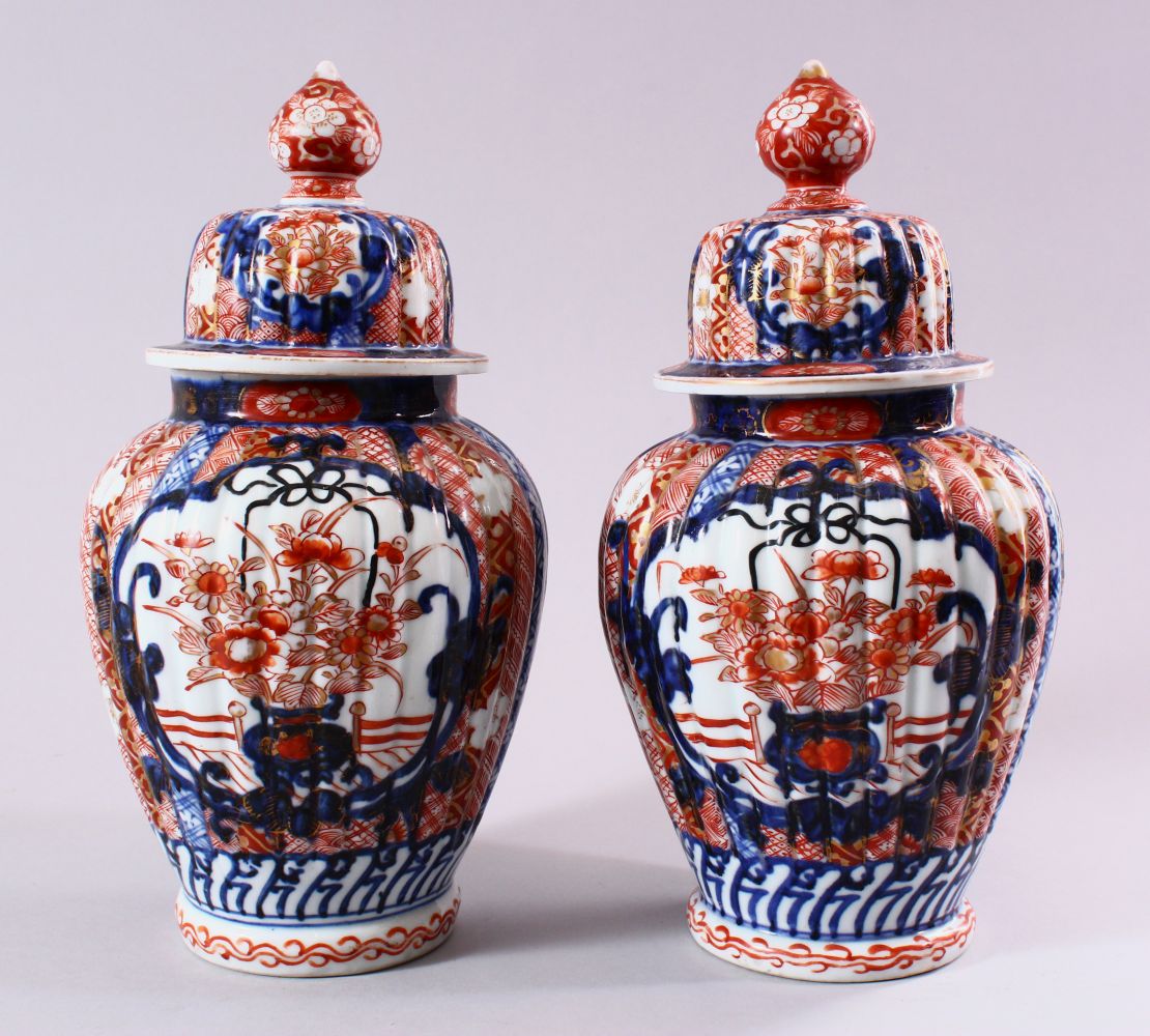 A PAIR OF JAPANESE MEIJI PERIOD IMARI PORCELAIN VASES & COVERS, with panel decoration depicting