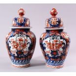 A PAIR OF JAPANESE MEIJI PERIOD IMARI PORCELAIN VASES & COVERS, with panel decoration depicting
