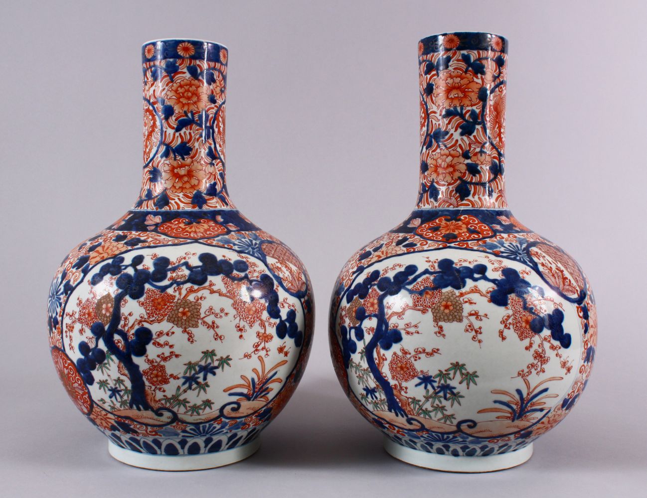 A PAIR OF JAPANESE MEIJI PERIOD IMARI PORCELAIN BOTTLE VASES, decorated with panels of the three