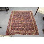 A small Persian Mashad rug, dark blue ground with rows of stylized decoration.