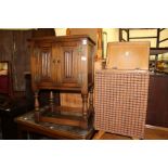 A small oak two door cupboard and a linen basket.