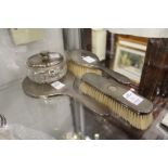 A four piece silver dressing table set comprising hand mirror, powder bowl and cover and two