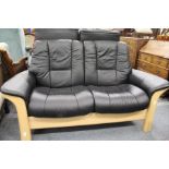 A Stressless beech framed and black leather upholstered two seater reclining settee.