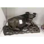 A Chinese 19th century carved hardwood model of a water buffalo on a pierced and carved stand.