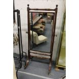 A 19th century mahogany cheval mirror with turned supports on four curving legs with brass castors.